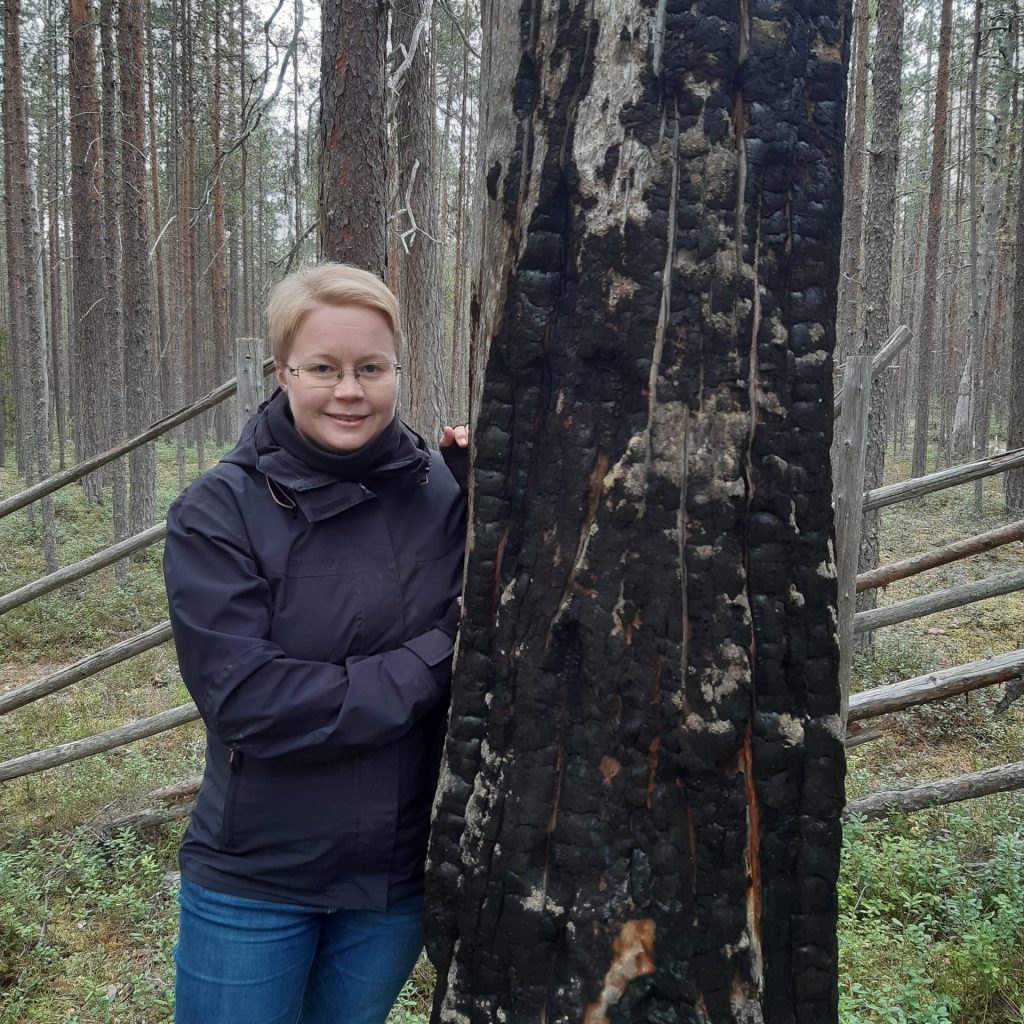 Niina Kuosmanen next to a charred stem